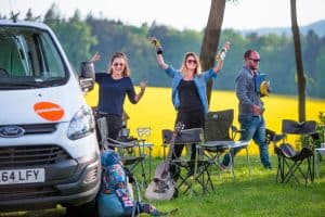 Campervan parked, travellers getting stuff from the van and setting up picnic area
