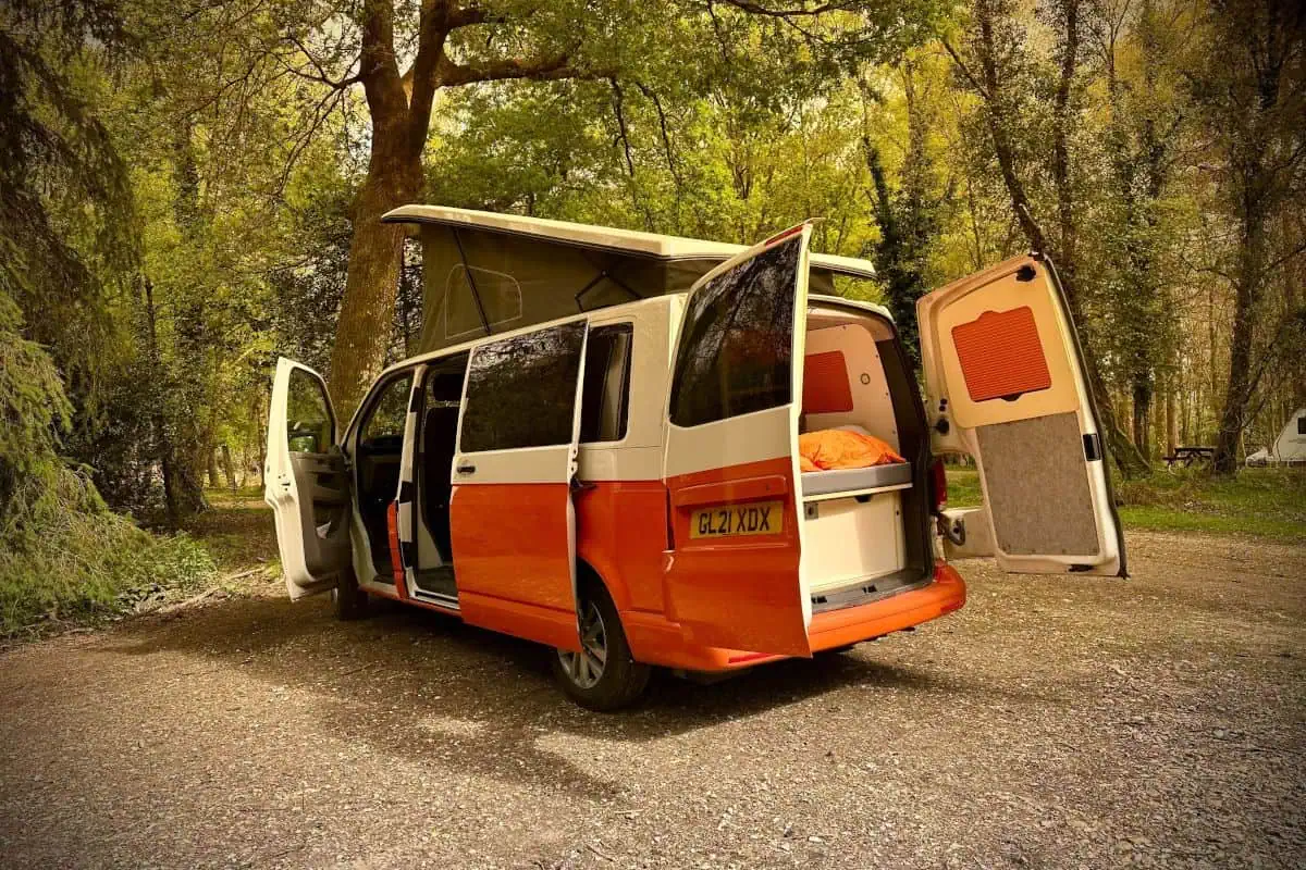 Rear view of the VW Cosmo Campervan with the trunk and back doors open, revealing a bed and storage space.