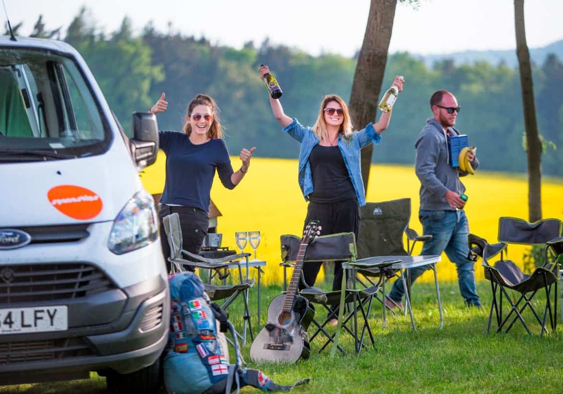 Campervan parked, travellers getting stuff from the van and setting up picnic area